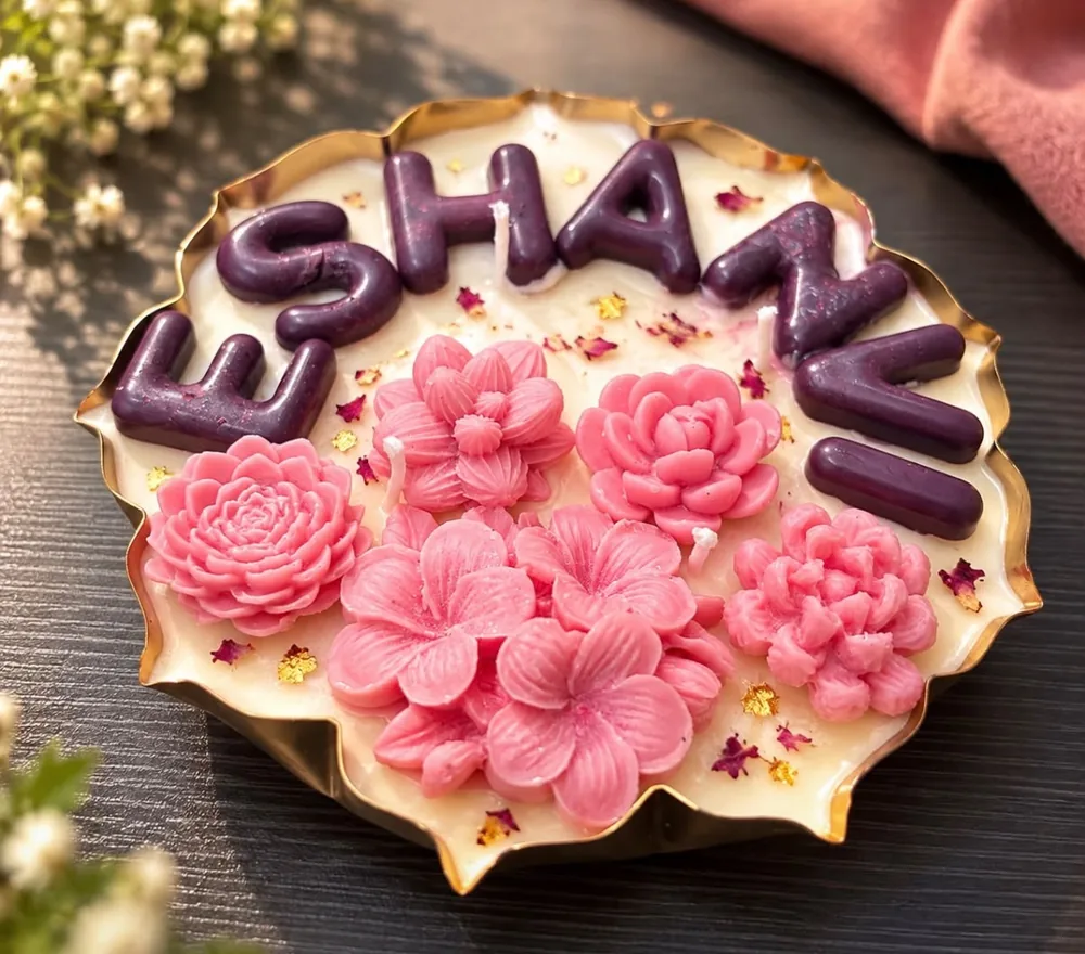 Personalised urli candle with a name in purple wax letters and pink flower candles